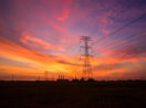 Pôr do sol com o céu nas cores laranja, rosa e azul e torres de energia ao fundo, alusivo aos bons dividendos da CPFL Energia