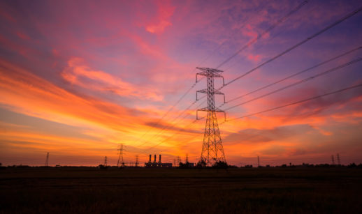 Pôr do sol com o céu nas cores laranja, rosa e azul e torres de energia ao fundo, alusivo aos bons dividendos da CPFL Energia