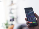 Tela de celular com gráfico de ações, alusivo às recomendações com foco em dividendos para março
