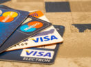 Quatro cartões sobre mesa, dois da Visa por baixo e dois da Mastercard por cima