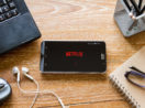 Mesa de madeira com celular ligado e logo da Netflix, criadora da série Stranger Things