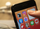 Close de celular com app do Instagram, que deve ter marketplace de NFTs, em destaque e dedo de pessoa próximo
