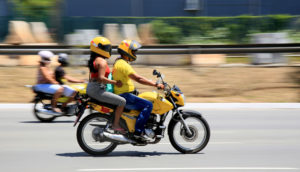 Duas motos amarelas em velocidade com duas pessoas em cada garupa, alusivo ao crescimento da produção