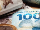 Cédulas de real com moeda ao lado, com destaque para nota de 100 reais, alusivo ao investimento em renda fixa