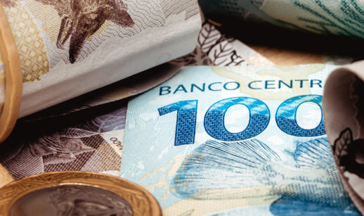 Cédulas de real com moeda ao lado, com destaque para nota de 100 reais, alusivo ao investimento em renda fixa