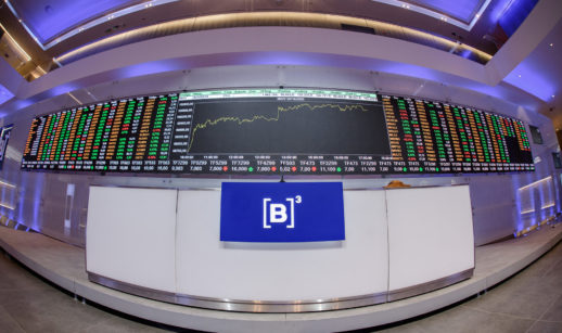 Interior da B3, com destaque para balcão com microfone e logo da empresa e telão de LED gigante com informações sobre o mercado financeiro, alusivo às top picks para investir em renda variável na semana