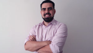 Felipe Chiconato, de camisa rosa clara e barba feita, sorrindo, olhando para frente