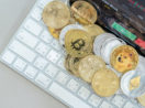 Conceito de criptomoedas de ouro e prata, materializadas sobre teclado de laptop, alusivo à Binance