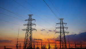 Pôr do sol com as silhuetas de torres de transmissão de energia, alusivo à manutenção do rating da S&P Global para a Eletrobras
