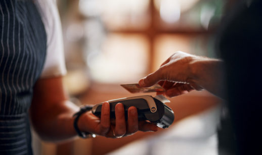 Close de pessoa aproximando o cartão de crédito a uma máquina de pagamento, alusivo ao financiamento