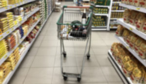 Carrinho de supermercado entre corredores e gôndolas embaçado, alusivo à inflação de 2022