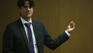 Bruno Aranha, diretor do BNDES, de terno preto e gravata azul, gesticulando de pé