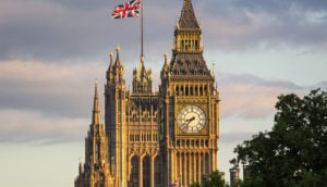 Parlamento do Reino Unido, para onde Elon Musk foi convidado a explicar transação com o Twitter, com destaque para bandeira britânica no alto e árvore à frente em primeiro plano