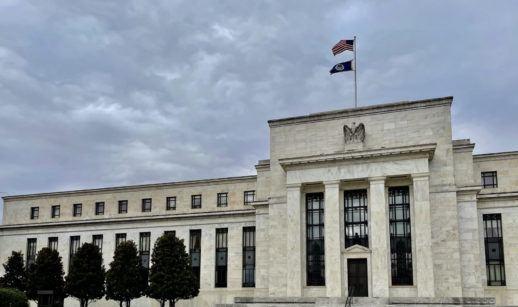 Fachada do Federal Reserve, Fed, o BC dos EUA, que define a política de juros, com destaque para bandeira do país e céu nublado
