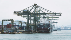 Terminal do Porto de Santos, com destaque para pontes rolantes sobre navio atracado, alusivo à prévia do PIB
