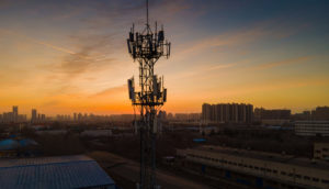 Torre de telecomunicações com pôr do sol atrás, alusivo às ações da TIM (TIMS3)