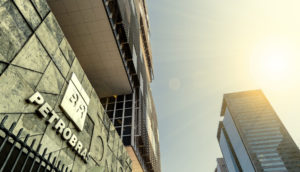 À esquerda, fachada da sede da Petrobras, cujas ações pagam bons dividendos, com destaque para o logo prateado e perspectiva de baixo para cima