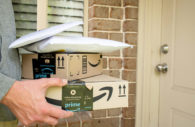 Mãos carregando duas caixas e dois pacotes de plástico do Amazon Prime Day 2022