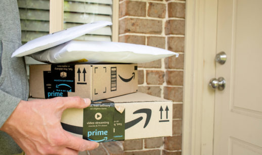 Mãos carregando duas caixas e dois pacotes de plástico do Amazon Prime Day 2022