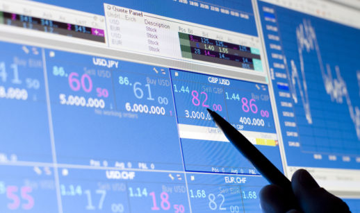 Gráficos de mercado financeiro em tela de tablet com mãos sobre ela, alusivo aos multimercados