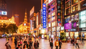 Pessoa andando em rua iluminada de Xangai, na China, que traz otimismo às bolsas asiáticas