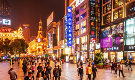 Pessoa andando em rua iluminada de Xangai, na China, que traz otimismo às bolsas asiáticas