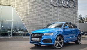 Audi Q3 na cor azul em frente à concessionária da empresa