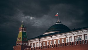 Kremlin, na Rússia, que deu calote em investidores, com bandeira do país em destaque sobre domo e céu escuro de chuva