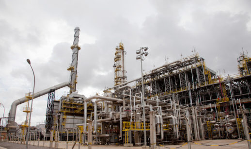 Refinaria Abreu e Lima (RNEST), uma das três refinarias que entrarão em venda da Petrobras, em Pernambuco, com destaque para diversos canos metálicos e céu nublado atrás