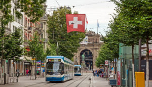 Rua de Zurique, onde fica o Banco Central da Suíça, com bonde andando e bandeira do país