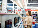 Mulher olhando gôndolas com TVs, alusivo às vendas no comércio em abril no Brasil