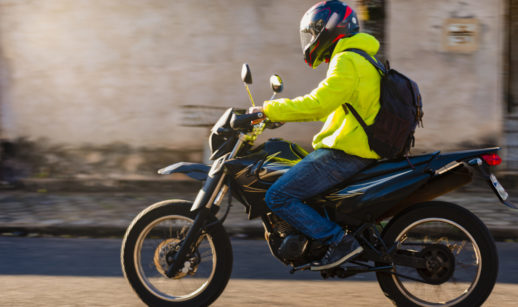 Motociclista com jaqueta amarela e capacete andando em motocicleta, alusivo às vendas de motos em maio que cresceram