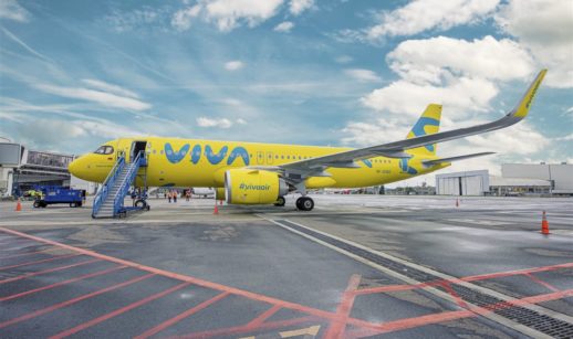 Avião amarelo da companhia low cost Viva parado em aeroporto com céu azul