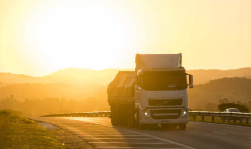 Caminhão rodando em estrada com pôr do sol ao fundo, alusivo ao crescimento dos serviços em maio