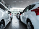 Duas fileiras de carros brancos dentro de concessionária, alusivo às vendas de veículos em junho