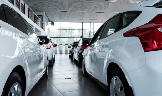 Duas fileiras de carros brancos dentro de concessionária, alusivo às vendas de veículos em junho