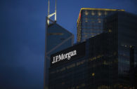 Fachada de prédio do JP Morgan espelhado, ao anoitecer, com destaque para o logo iluminado em branco