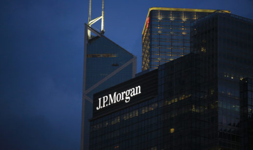 Fachada de prédio do JP Morgan espelhado, ao anoitecer, com destaque para o logo iluminado em branco