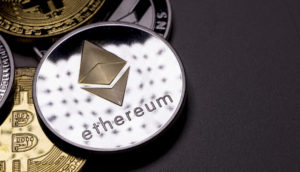 Conceito da moeda Ethereum, na cor prateada, sobre outros criptos em mesa cinza