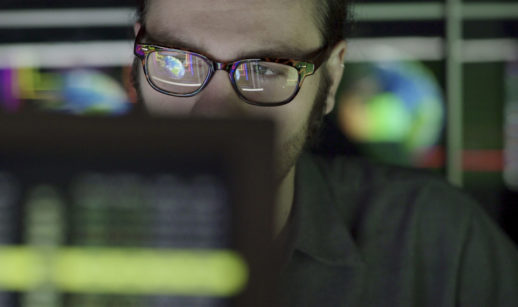 Homem de óculos olhando para tela de computador com desenho da Terra ao fundo, alusivo ao Hackathon de Big Data da ONU
