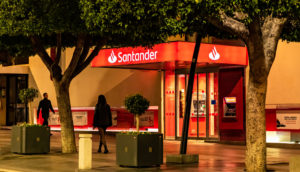 Fachada de agência do Santander (SANB11) na cor vermelha, com árvores na frente