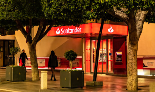 Fachada de agência do Santander (SANB11) na cor vermelha, com árvores na frente