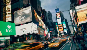 Times Square, em Nova York, à noite, com movimento em freezee, alusivo ao crescimento dos EUA e da Europa