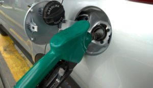 Close de bomba de combustível presa a tanque de carro, alusivo a um posto da Petrobras que reduziu o preço do litro da gasolina