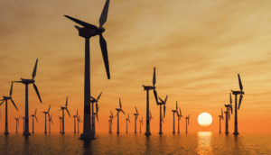 Turbinas de geração de energia eólica em alto mar com pôr do sol ao fundo