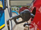 Close de bomba de gasolina, que ajudou a segurar a inflação dos EUA em julho, abastecendo carro vermelho