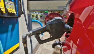 Close de bomba de gasolina, que ajudou a segurar a inflação dos EUA em julho, abastecendo carro vermelho