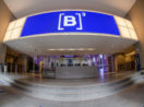 Entrada da B3, com destaque para o balcão de entrada com letreiro luminoso em azul e logo da Bolsa, que tem diferentes regras de governança corporativa para as listagens