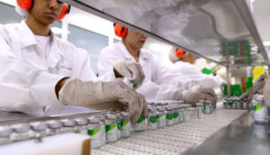 Linha de produção de farmoquímicos, com destaque para mãos de funcionários em frascos, o setor que puxou a queda da produção industrial de junho