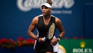 Serena Williams, de roupa preta e viseira branca, jogando tênis, do qual anunciou a aposentadoria